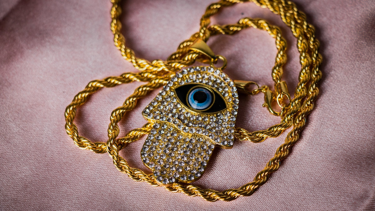 a gold necklace with an evil eye on it