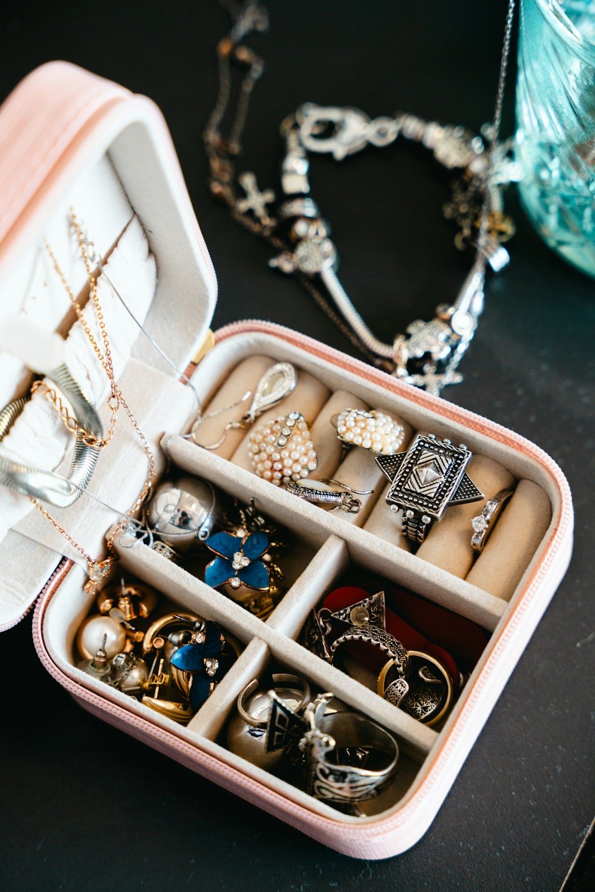 A pink jewelry box filled with necklaces and rings.