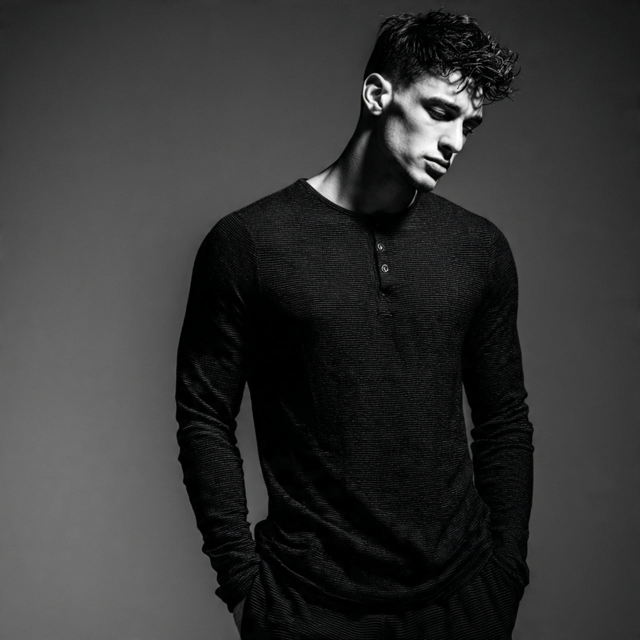 Male model wearing a modern casual top, clean monochromatic studio setting, sharp lighting, premium editorial styling, luxury menswear aesthetic