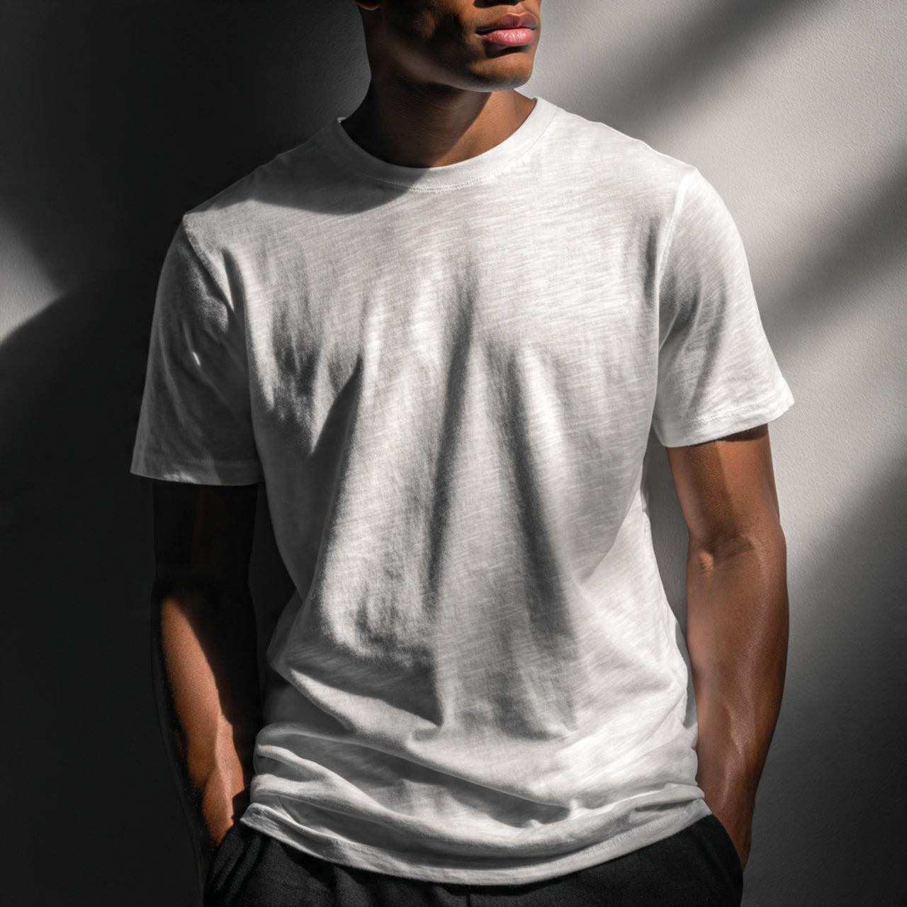 Male model wearing crisp premium t-shirt, neutral studio background, soft directional lighting, focus on fabric texture and fit, modern minimal editorial style