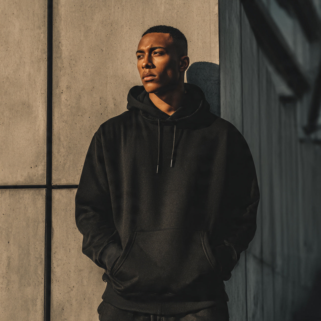 Stylish male model in high-quality hoodie, urban minimal background, matte tones, premium streetwear vibe, editorial photography,